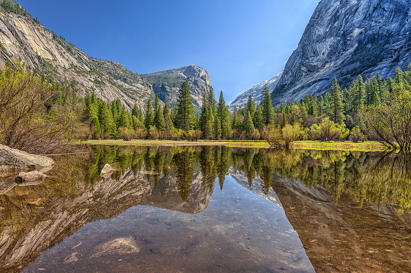Nearby trees and mountains are shown flawlessly reflected on Mirror Lake.