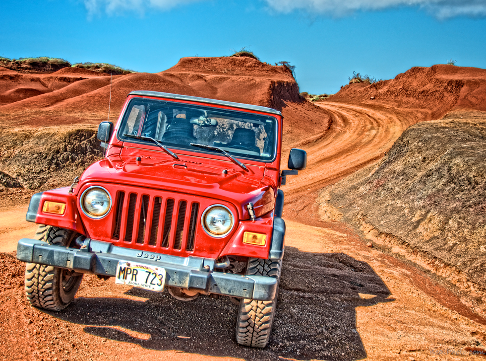 Red Jeep Wrangler off roading on the dirt trails of Lanai.