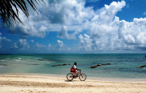 A woman rides her bike along the beach of San Pedro on Ambergris Caye